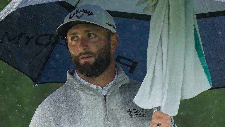 Jon Rahm, of Spain, waits to play in the rain on the 18th hole during the weather delayed second round of the Masters golf tournament at Augusta National Golf Club on Saturday, April 8, 2023, in Augusta, Ga. (AP Photo/Charlie Riedel)