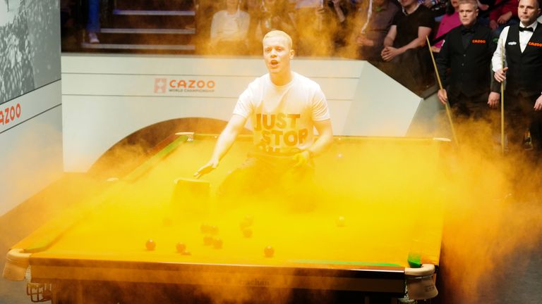 A protester jumps on the table during the match between Robert Milkins and Joe Perry